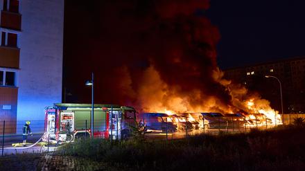 Die Feuerwehr versucht nach einem mutmaßlichen Brandanschlag in Berlin-Lichtenberg brennende Kleintransporter zu löschen. 