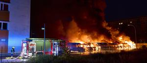 Die Feuerwehr versucht nach einem mutmaßlichen Brandanschlag in Berlin-Lichtenberg brennende Kleintransporter zu löschen. 