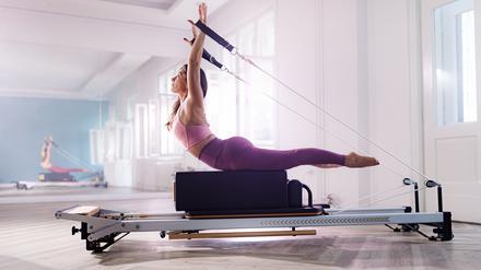 Eine Frau trainiert an einer Pilates-Maschine. 