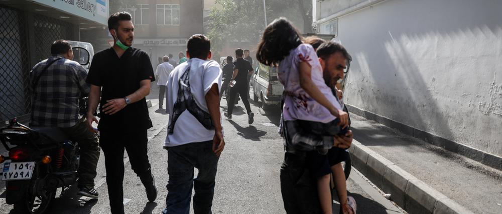 Menschen rennen am Sonntag nach einem israelischen Luftangriff durch die Straßen Teherans.