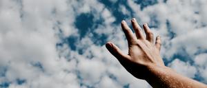 Eine Hand streckt sich Richtung Himmel.