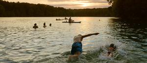Leute nutzen einen schönen Sommerabend am Schlachtensee zum Baden.