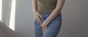 Eine Frau fasst sich aufgrund von Schmerzen in den Schritt.