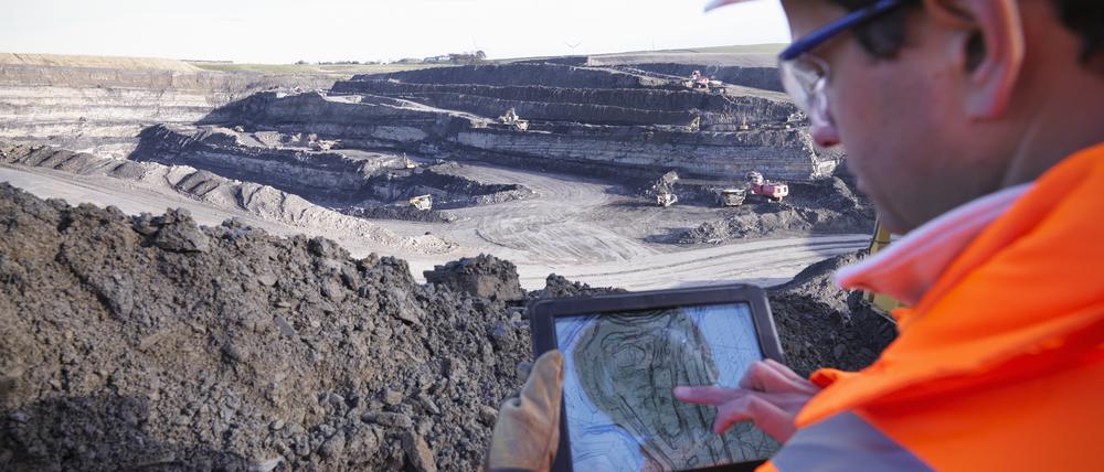 Ein Archäologe analysiert mit einem Tablet die Oberfläche einer Kohlemine.