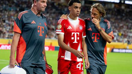 Jamal Musiala musste nur 25 Minuten nach seiner Einwechselung angeschlagen vom Platz, begleitet von Teamarzt (r) und Physiotherapeut. 