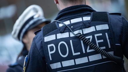Eine Polizistin (l) und ein Polizist gehen eine Straße entlang 