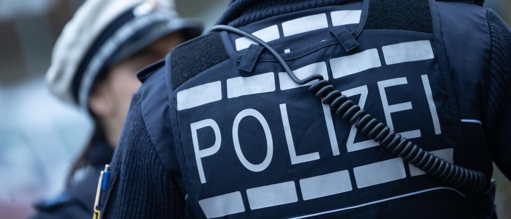 Eine Polizistin (l) und ein Polizist gehen eine Straße entlang 