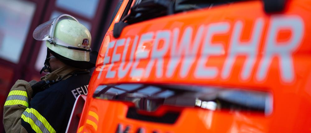 Eine Einsatzkraft der Feuerwehr steht neben einem Einsatzfahrzeug der Feuerwehr (gestellte Szene).