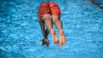 Ein Junge springt im Sommerbad Neukölln ins Schwimmbecken.