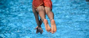 Ein Junge springt im Sommerbad Neukölln ins Schwimmbecken.