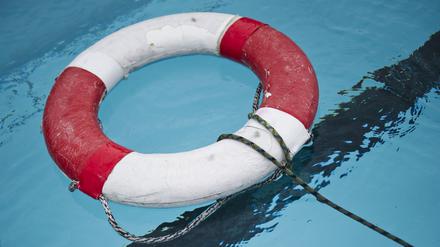 Ein Rettungsring liegt in einem Freibad im Wasser.