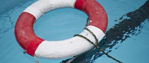 Ein Rettungsring liegt in einem Freibad im Wasser.