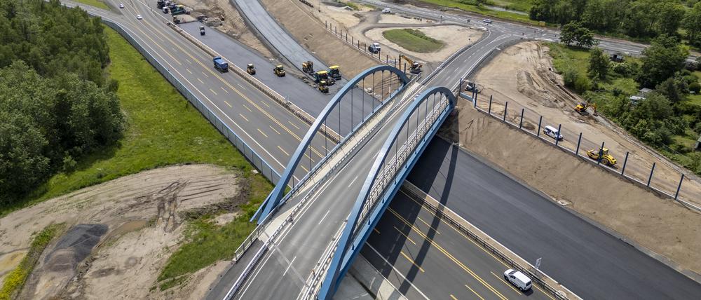 Autos und Lkw rollen über die neue A72 und die fertiggestellte Anschlussstelle Zwenkau, während im Hintergrund die Fahrbahn Richtung Chemnitz asphaltiert wird.