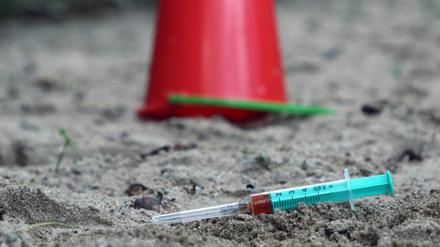 Die Einwegspritze einer drogenabhängigen Person liegt zurückgelassen auf einem Kinderspielplatz. (Symbolbild)