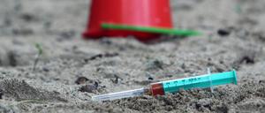 Die Einwegspritze einer drogenabhängigen Person liegt zurückgelassen auf einem Kinderspielplatz. (Symbolbild)