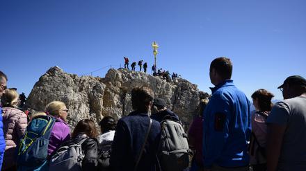 Bergsteiger und Wanderer stehen beim Gipfelkreuz auf der Zugspitze (Symbolbild).