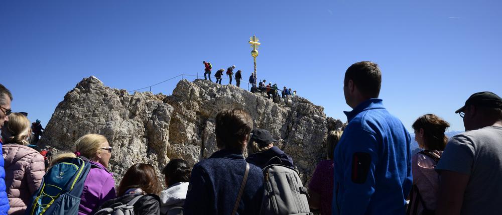 Bergsteiger und Wanderer stehen beim Gipfelkreuz auf der Zugspitze (Symbolbild).