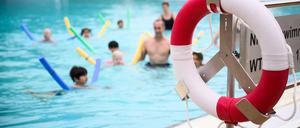 Ein Rettungsring hängt neben einem Schwimmbecken, in dem Kinder schwimmen lernen. (Symbolbild)