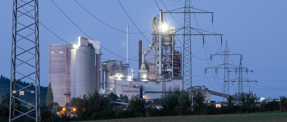 Strommasten stehen im Morgenlicht vor einem Zementwerk: Firmen mit hohem Stromverbrauch sollen staatliche Subventionen erhalten dürfen.