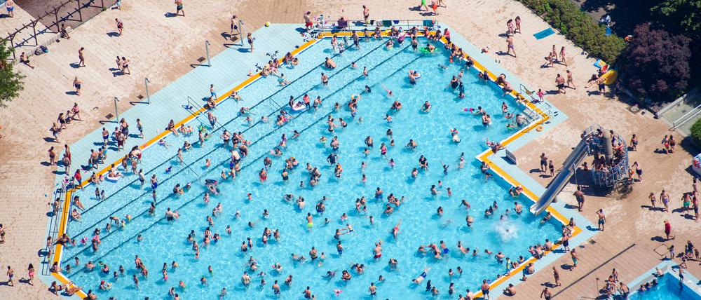 Kinder und Erwachsene baden und sonnen sich im Sommerbad Mariendorf. (Luftaufnahme).