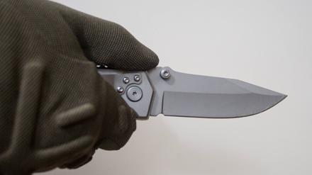 Person hält vor einem neutralen Hintergrund ein Messer in der Hand. (Symbolbild)