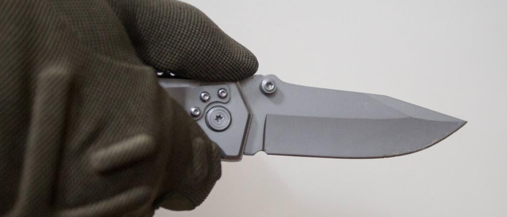 Person hält vor einem neutralen Hintergrund ein Messer in der Hand. (Symbolbild)