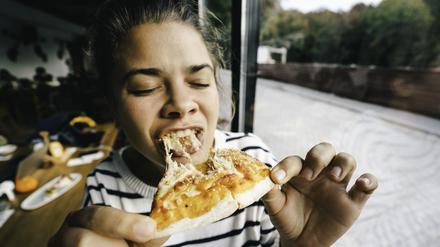 Wenn es schnell gehen muss: Eine Frau beißt in eine Pizza.