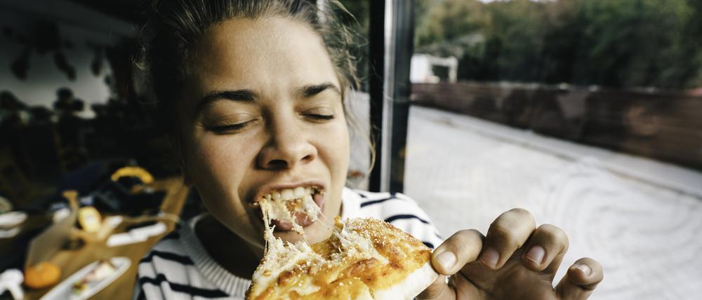 Wenn es schnell gehen muss: Eine Frau beißt in eine Pizza.