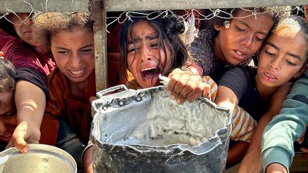 Palästinensische Kinder versuchen im Gebiet Al-Mawasi im Gazastreifen, mit ihren Töpfen Nahrungsmittel zu bekommen, die von Wohltätigkeitsorganisationen verteilt werden.
