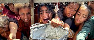 Palästinensische Kinder versuchen im Gebiet Al-Mawasi im Gazastreifen, mit ihren Töpfen Nahrungsmittel zu bekommen, die von Wohltätigkeitsorganisationen verteilt werden.