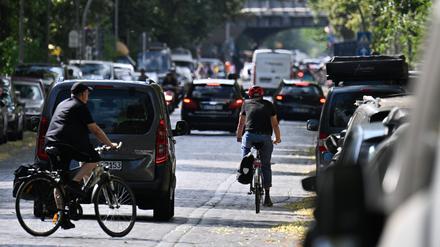 Autos, Fahrradfahrer und Fußgänger sind auf einer Straße im Stadtteil Kreuzberg unterwegs. 