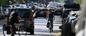 Autos, Fahrradfahrer und Fußgänger sind auf einer Straße im Stadtteil Kreuzberg unterwegs. 