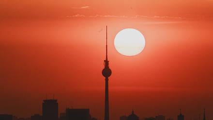Die Sonne hinter der Silhouette von Berlin.