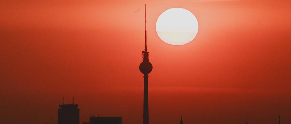 Die Sonne hinter der Silhouette von Berlin.