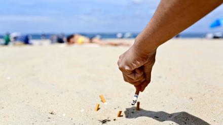 Ein Raucher drückt an einem Strand in Frankreich eine Zigarette aus.