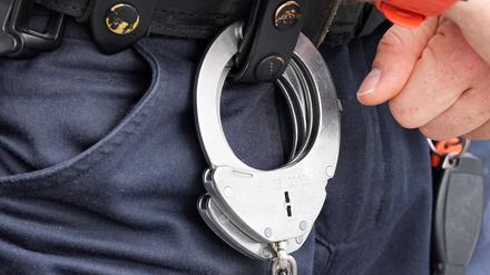 Handfesseln aus Metall hängen am Gürtel eines Polizisten. (Symbolbild)