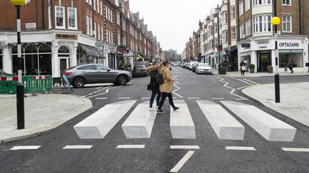 Zwei Fußgängerinnen gehen über den ersten 3D-Zebrastreifen Großbritanniens in St. Johns Wood.
