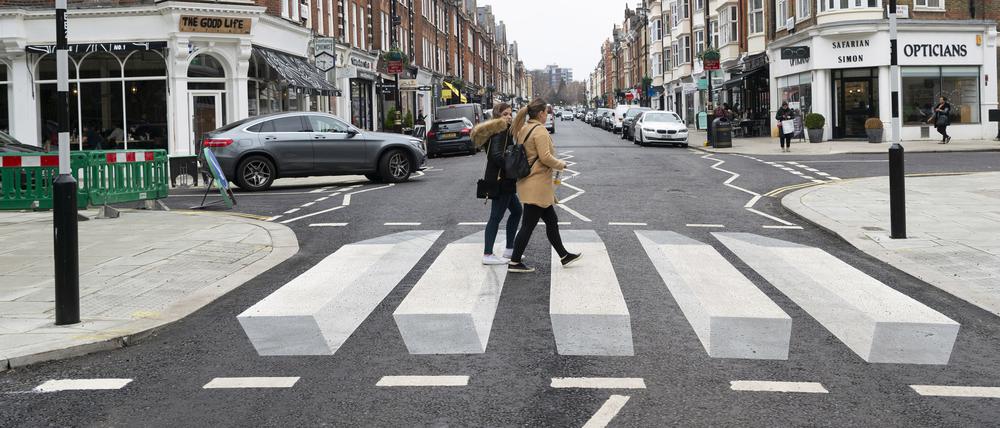 Zwei Fußgängerinnen gehen über den ersten 3D-Zebrastreifen Großbritanniens in St. Johns Wood.