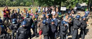 Demonstrierende und Polizisten stehen im Görlitzer Park. 