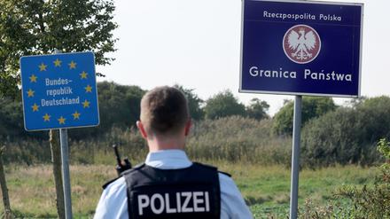 Ein Bundespolizist steht vor den Schildern für Deutschland und Polen. Als Reaktion auf die deutschen Kontrollen will nun auch Polen an der Grenze kontrollieren. (Archivbild)