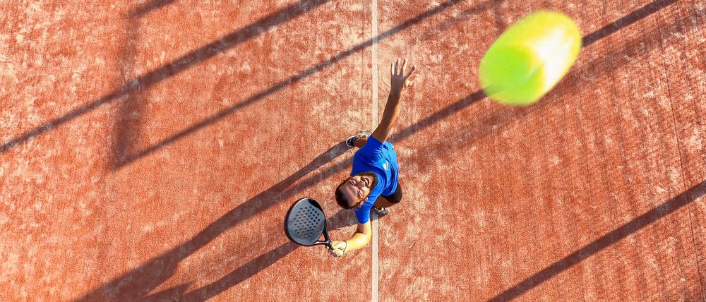 View from above of a professional padel player who is going to hit the ball during a padel match. The ball is very close to the camera.