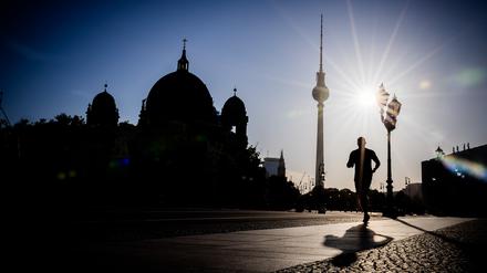 Ein Jogger rennt am frühen Morgen vor dem Berliner Fernsehturm und dem Dom.