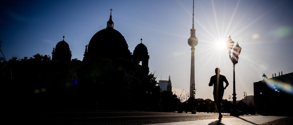 Ein Jogger rennt am frühen Morgen vor dem Berliner Fernsehturm und dem Dom.