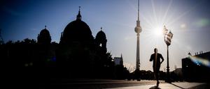 Ein Jogger rennt am frühen Morgen vor dem Berliner Fernsehturm und dem Dom.