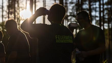 Einsatzkräfte der Feuerwehr stehen für eine kurze Pause in einem Waldstück bei Babben im Elbe-Elster-Kreis. Im südbrandenburgischen Elbe-Elster-Kreis ist ein großflächiger Waldbrand ausgebrochen.