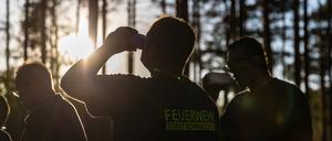 Einsatzkräfte der Feuerwehr stehen für eine kurze Pause in einem Waldstück bei Babben im Elbe-Elster-Kreis. Im südbrandenburgischen Elbe-Elster-Kreis ist ein großflächiger Waldbrand ausgebrochen.