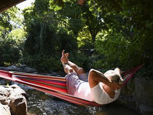 Ein Mann schaukelt im Viktoriapark auf dem Kreuzberg in einer Hängematte über dem Wasser. 