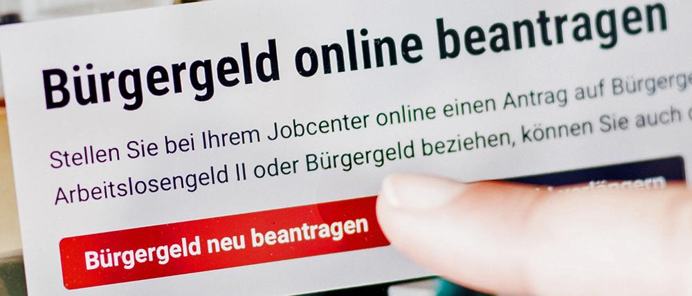 Eine Frau tippt auf einem Tablet auf einen Link zum Beantragen des Bürgergeldes im Kundenbereich im Jobcenter Berlin Mitte.