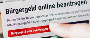 Eine Frau tippt auf einem Tablet auf einen Link zum Beantragen des Bürgergeldes im Kundenbereich im Jobcenter Berlin Mitte.