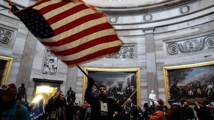 Eine Person schwenkt die US-Flagge im Inneren des US-Kapitols, nachdem Anhänger des damaligen US-Präsidenten Trump das Gebäude gestürmt hatten (Symbolbild).